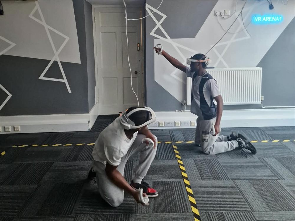 Two friends in VR headsets kneeling and aiming in a Blitz Arcade game at VR Arena 1